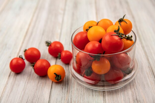 Vista superior de tomates vermelhos frescos em uma tigela de vidro em uma superfície cinza de madeira