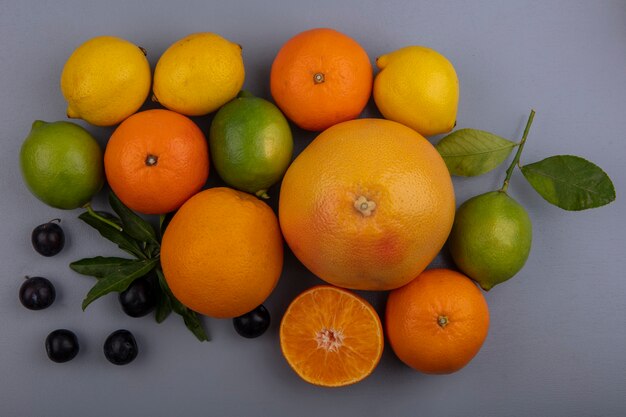 Vista superior de toranja com laranja, limão, limão e ameixa cereja em fundo cinza