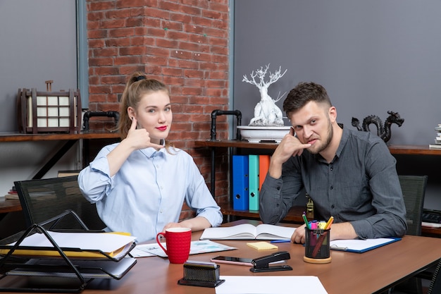 Foto grátis vista superior de trabalhadores qualificados sorridentes e motivados fazendo gesto de me ligar no escritório