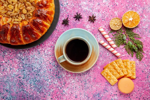 Foto grátis vista superior de um bolo delicioso com chá de passas e biscoitos na mesa rosa