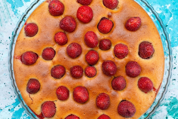 Foto grátis vista superior de um delicioso bolo de morango redondo em forma de frutas em cima e por dentro em uma mesa azul brilhante, massa de bolo, biscoito doce, açúcar