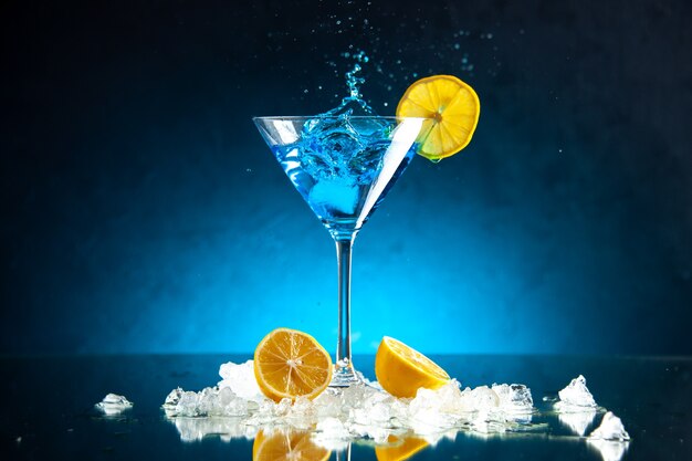 Vista superior de um delicioso coquetel em uma taça de vidro servido com uma fatia de gelo de limão no fundo azul