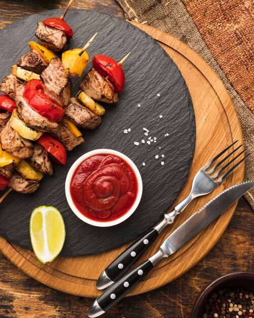 Vista superior de um delicioso kebab em ardósia com ketchup e talheres