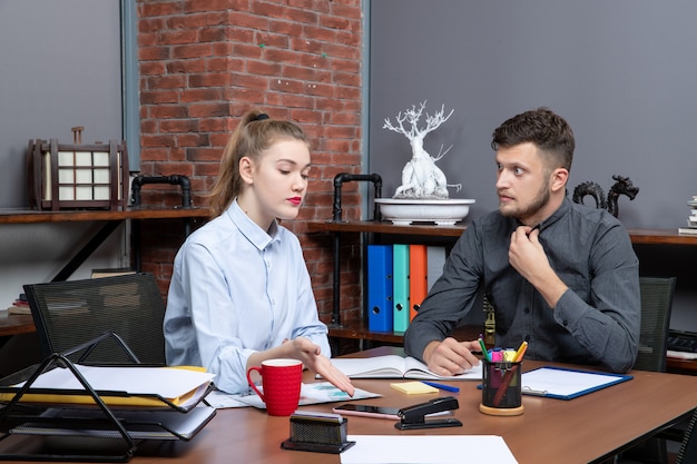 Vista superior de um jovem surpreso e uma colega de trabalho discutindo um problema no ambiente de escritório