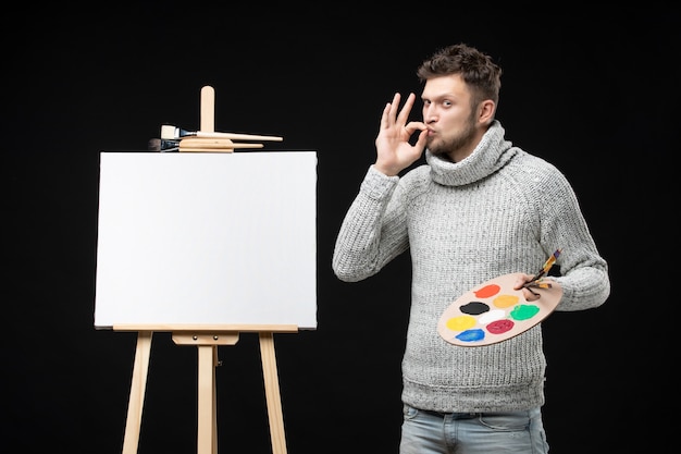 Foto grátis vista superior de um jovem talentoso e ambicioso pintor masculino fazendo gesto de óculos em preto isolado