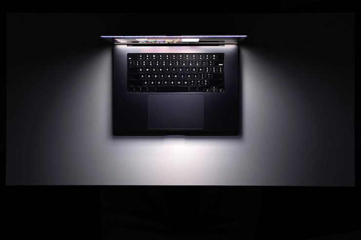 Foto grátis vista superior de um laptop em uma tela brilhante de mesa no escuro