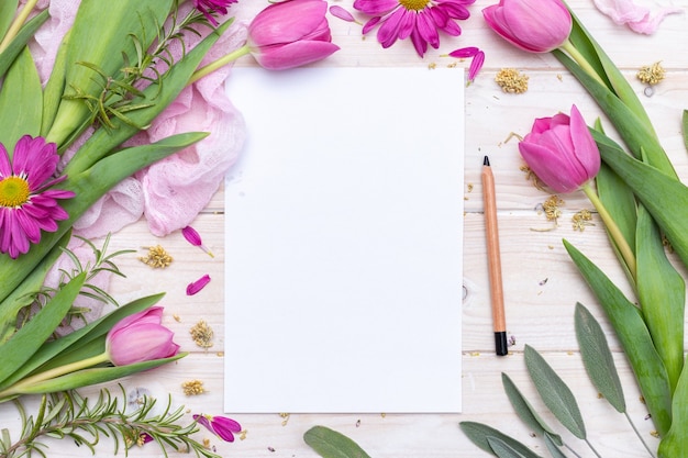 Vista superior de um papel em branco e um lápis decorado com flores roxas