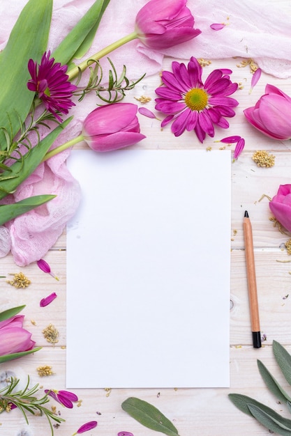 Vista superior de um papel em branco e um lápis decorado com flores roxas