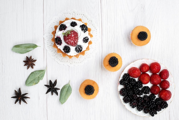 Vista superior de um pequeno bolo delicioso com biscoitos de creme e bagas em branco, biscoito de bolo assar frutas doce baga