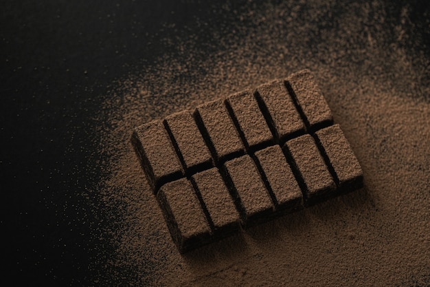 Foto grátis vista superior de uma barra de chocolate amargo polvilhada com cacau em pó