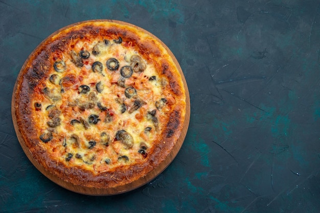 Vista superior de uma deliciosa pizza cozida com queijo e azeitonas na mesa azul escura