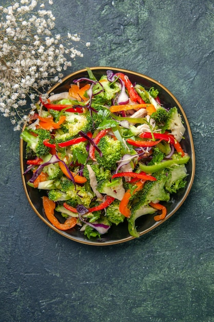 Vista superior de uma deliciosa salada de vegetais com vários ingredientes em uma tábua de corte preta