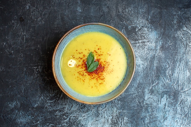 Foto grátis vista superior de uma deliciosa sopa servida com pimenta e hortelã em uma panela azul sobre fundo escuro