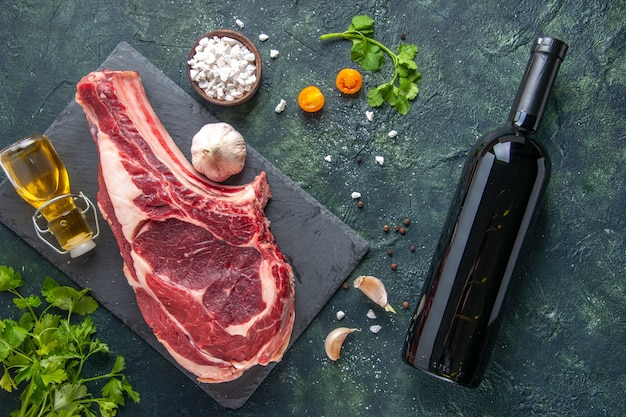 Vista superior de uma grande fatia de carne crua com verduras na superfície escura