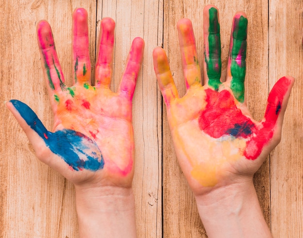 Foto grátis vista superior de uma mão pintada colorida mãos na mesa de madeira