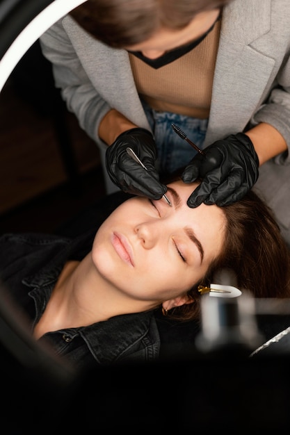Foto grátis vista superior de uma médica fazendo um tratamento de sobrancelha para uma mulher