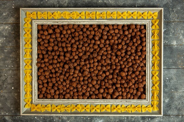 Vista superior de uma moldura de madeira com macarrão farfalle e preenchido com bolas de milho de cereais de chocolate
