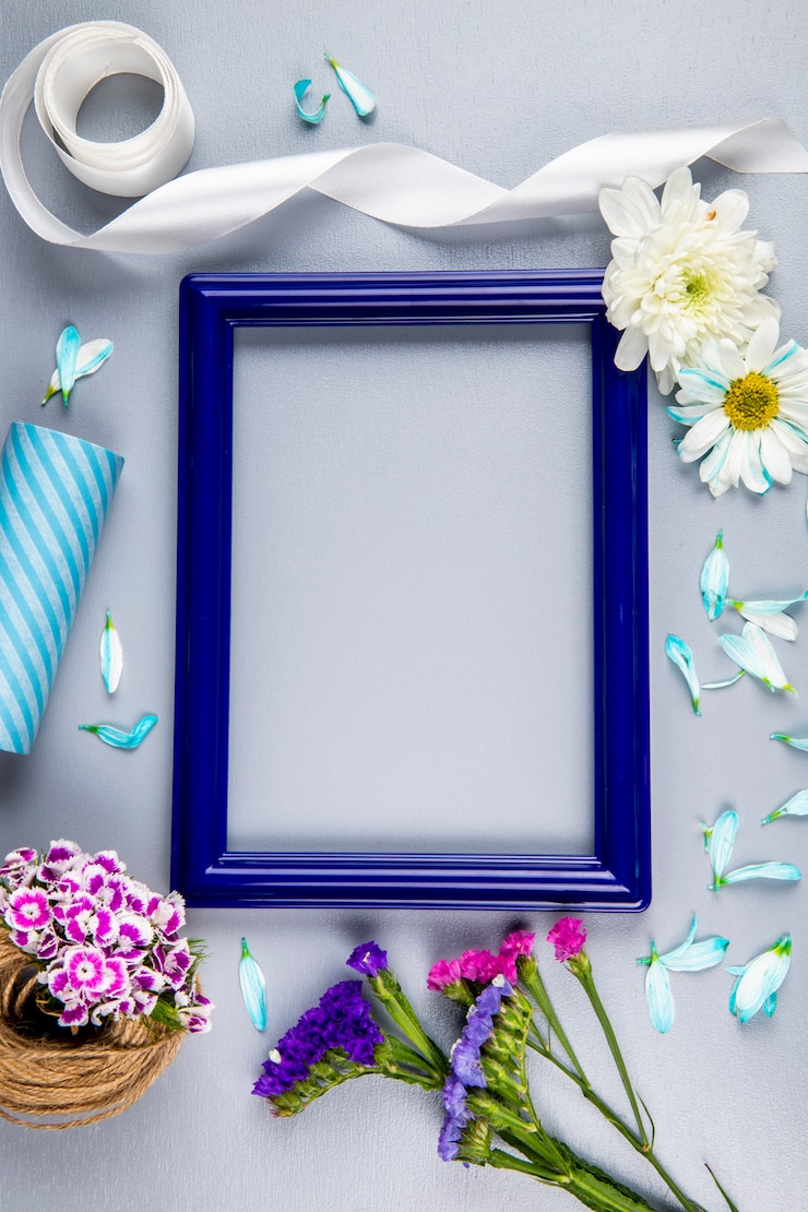 Foto grátis vista superior de uma moldura vazia com flores de statice de cor roxa e rosa e flores e pétalas de crisântemo, um novelo de corda com cravo turco na mesa branca com espaço de cópia