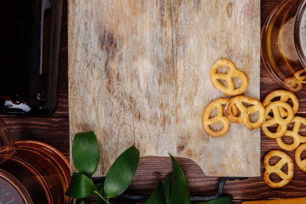 Vista superior de uma placa de madeira com mini pretzels e cerveja no rústico, com espaço de cópia