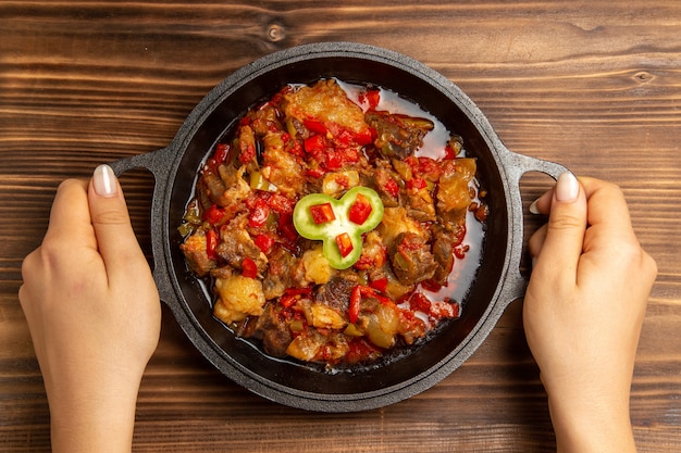 Vista superior de uma refeição de vegetais cozidos dentro da panela na mesa marrom