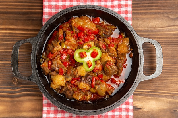 Vista superior de uma refeição de vegetais cozidos, incluindo vegetais e carne dentro de uma mesa de madeira marrom