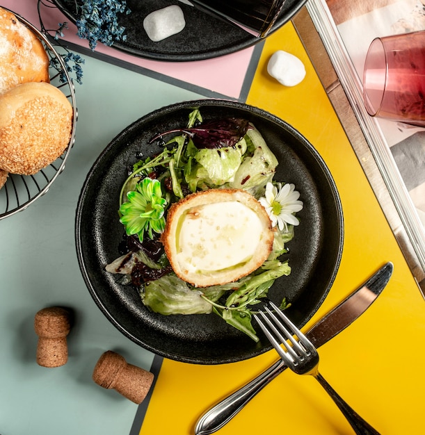 Vista superior de uma tigela de frango à milanesa, cheia de queijo e alface