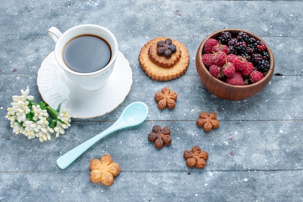 Vista superior de uma xícara de café junto com biscoitos e frutas frescas em um biscoito de biscoito de massa doce de madeira cinza