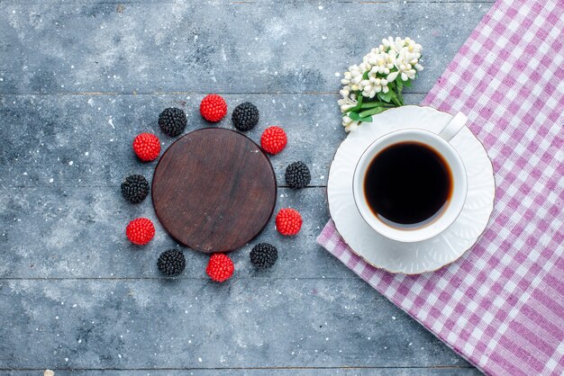 Vista superior de uma xícara de café junto com frutas confiture em um bolo de açúcar cinza e doce