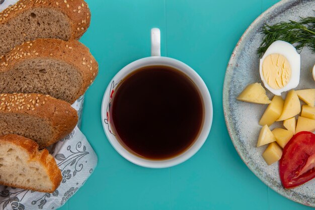 Vista superior de uma xícara de chá com pães e ovo, batata, tomate, endro, sobre fundo azul