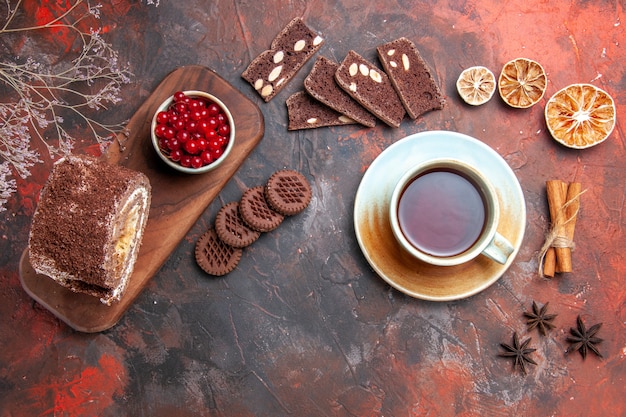 Vista superior de uma xícara de chá com rolo de biscoito na superfície escura