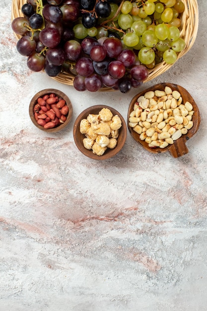 Foto grátis vista superior de uvas frescas com nozes na superfície branca