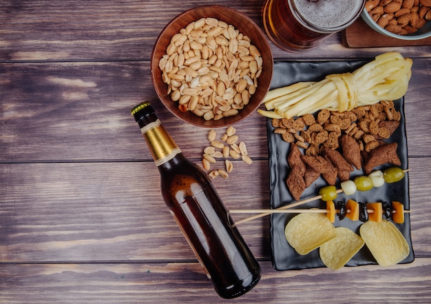 Vista superior de variados lanches de cerveja com uma garrafa de cerveja no rústico, com espaço de cópia