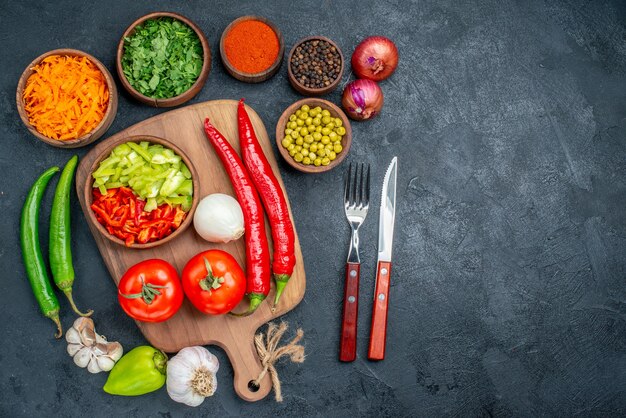 Vista superior de vegetais frescos com verduras e feijões em uma mesa escura para salada de vegetais maduros