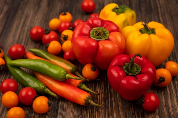 Vista superior de vegetais maduros, como tomate cereja e pimentão, isolados em uma parede de madeira