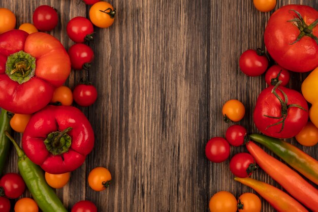 Vista superior de vegetais saudáveis, como tomates e pimentões isolados em uma parede de madeira com espaço de cópia