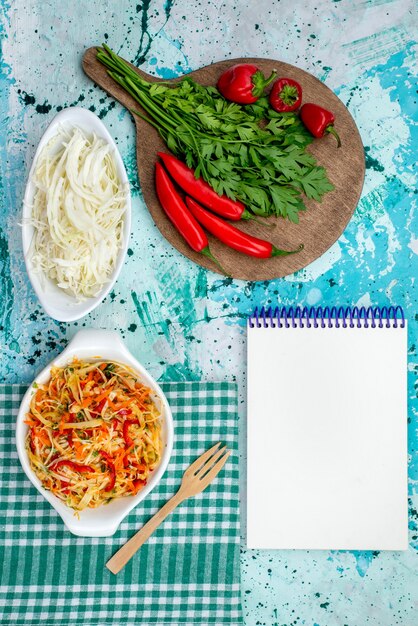 vista superior de verduras frescas junto com bloco de notas de salada de pimentão vermelho picante e repolho em refeição de comida verde vegetal azul brilhante