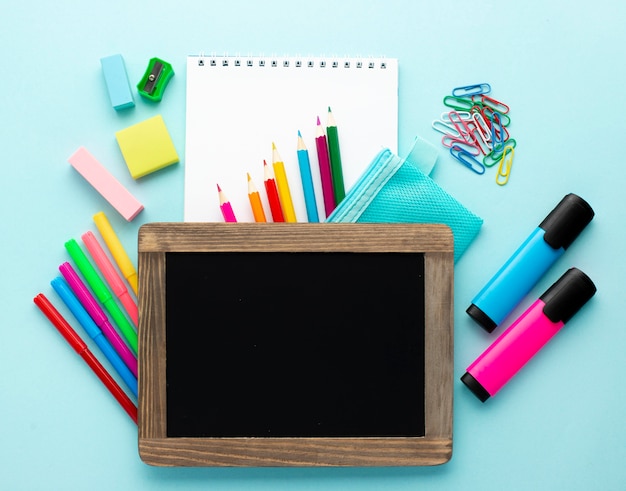 Vista superior de volta aos artigos de papelaria da escola com lápis coloridos e quadro-negro