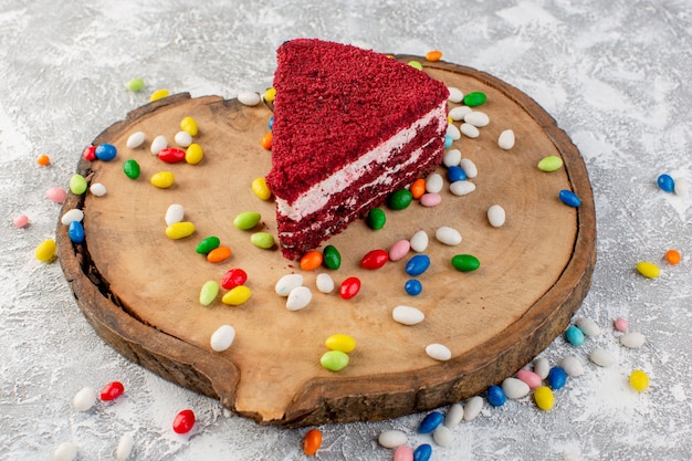 Vista superior deliciosa fatia de bolo com creme e frutas sobre a mesa de madeira com doces coloridos