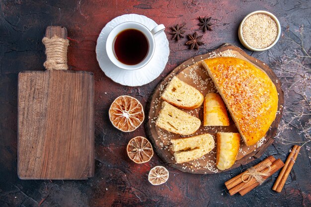 Vista superior deliciosa massa doce com uma xícara de chá na superfície escura