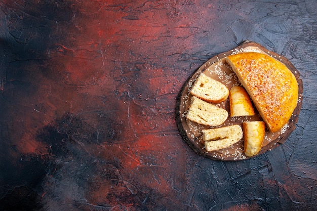 Vista superior deliciosa massa doce fatiada em pedaços na superfície escura