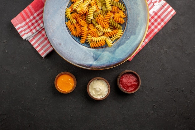 Vista superior deliciosa massa italiana incomum macarrão espiral cozido dentro do prato no fundo escuro