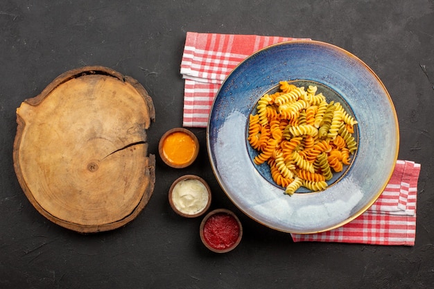 Vista superior deliciosa massa italiana incomum macarrão espiral cozido em prato escuro de mesa