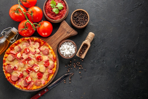 Vista superior deliciosa pizza com tomates vermelhos frescos na mesa escura