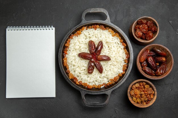 Vista superior deliciosa refeição de arroz cozido plov com passas dentro da panela na mesa escura