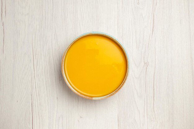 Vista superior deliciosa sopa creme prato amarelo na mesa branca sopa molho refeição creme prato jantar