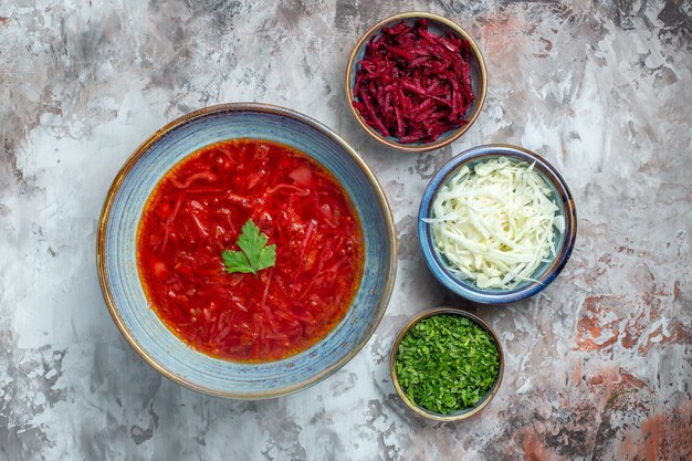 Vista superior deliciosa sopa de beterraba ucraniana com repolho fresco e verduras no fundo branco