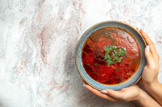 Vista superior deliciosa sopa de beterraba ucraniana famosa borsch com carne dentro do prato em um espaço em branco claro