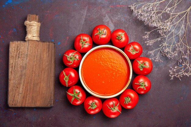Vista superior deliciosa sopa de tomate circulada com tomates vermelhos frescos em fundo escuro prato de sopa de tomate molho refeição