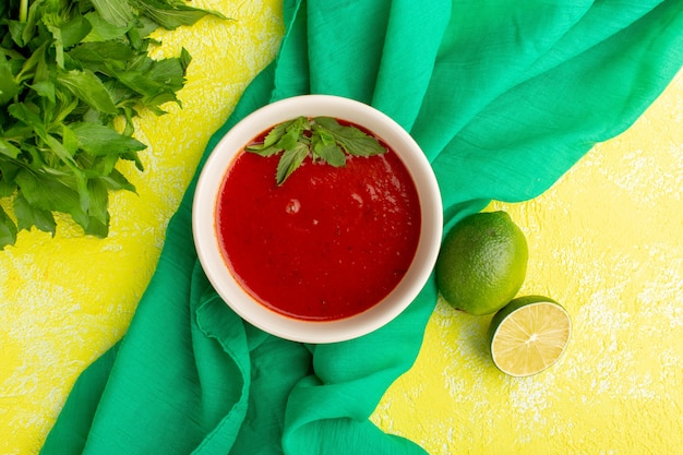 Vista superior deliciosa sopa de tomate com limão e verduras na mesa amarela, sopa comida refeição jantar