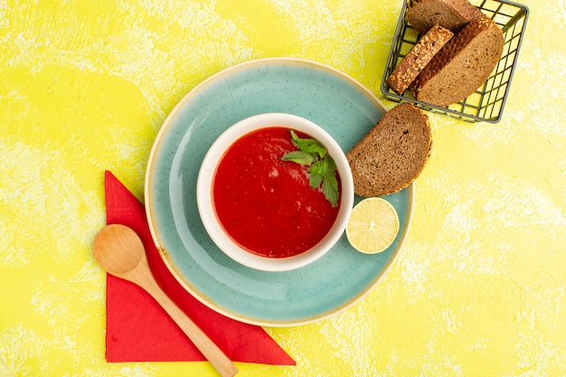 Vista superior deliciosa sopa de tomate com pães na mesa amarela, refeição de sopa, jantar de vegetais